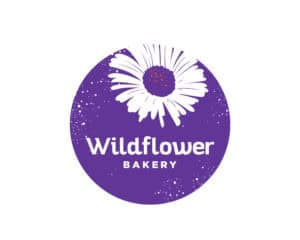 Wildflower Bakery logo design with a vibrant purple circular background and a delicate daisy—designed by Inspiring Design Co. to represent natural ingredients and artisanal baking.
